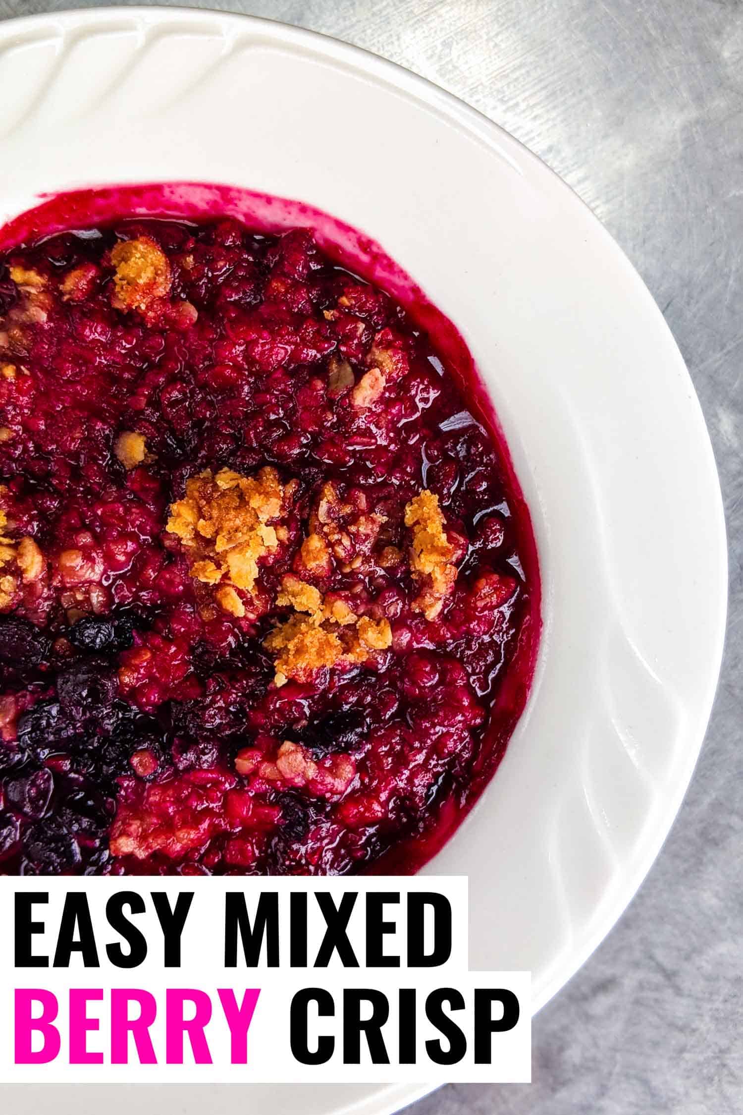 Mixed berry crisp recipe in white bowl on silver background, a classic Nova Scotian dessert.