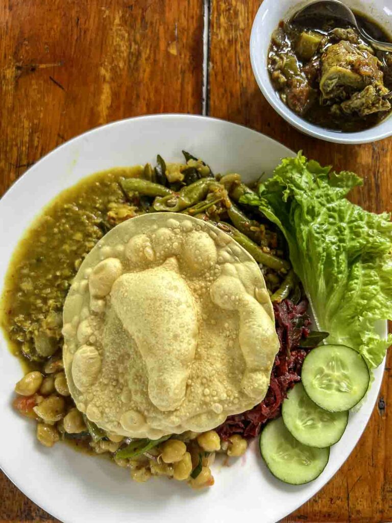 plate of vegetarian rice and curry with dal, chickpease, beetroot and papadam on top