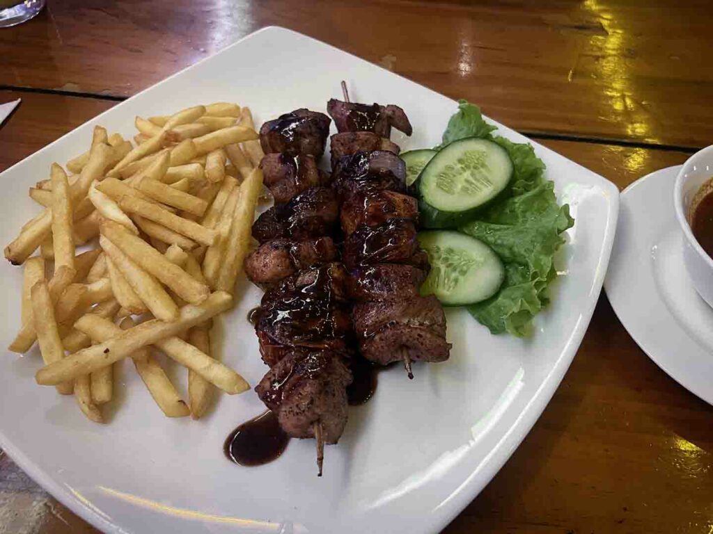 beef kebabs and fries on white plate with cucumber and lettuce garnish
