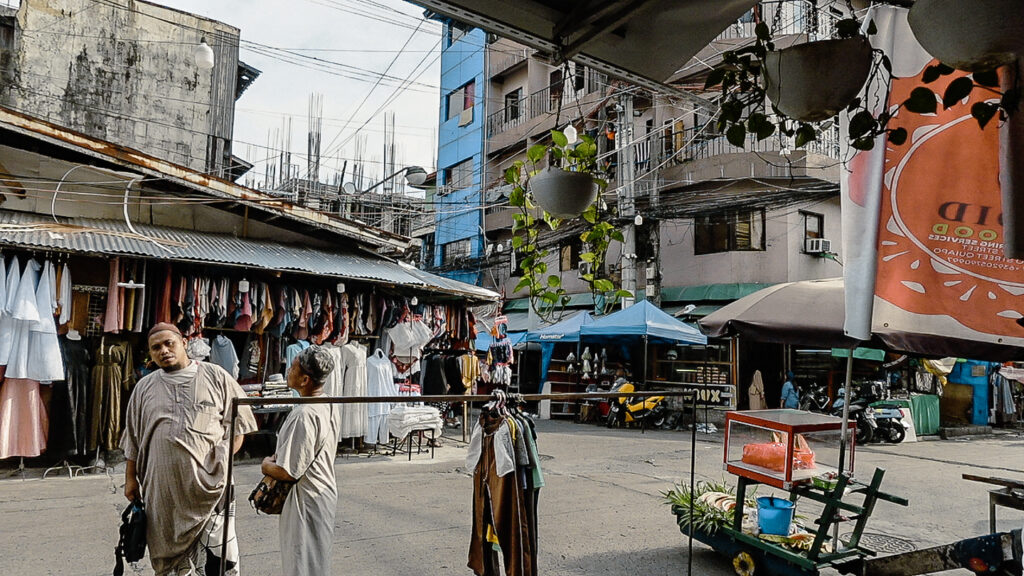 Typical street scene in Muslim town in Quiapo Manila showing men on streets and clothing stores