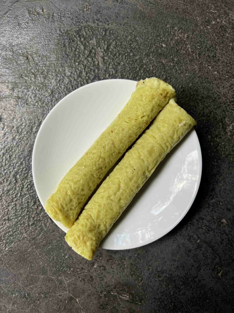 Daral sweet in Philippines and popular Muslim food of crepe with sweet coconut filling, served on a white plate and rustic background