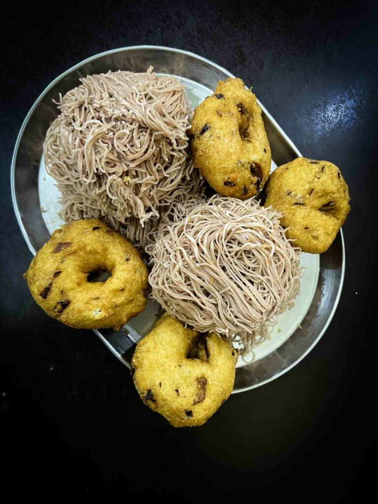 Nallur Kandaswamy food Vada and string hoppers on dark tabletop