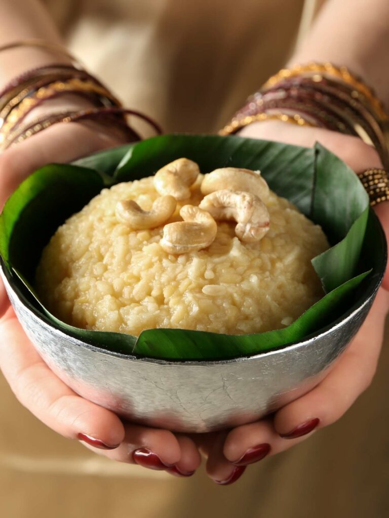 Pongal, sweet rice pudding, in a woman's hands serving it