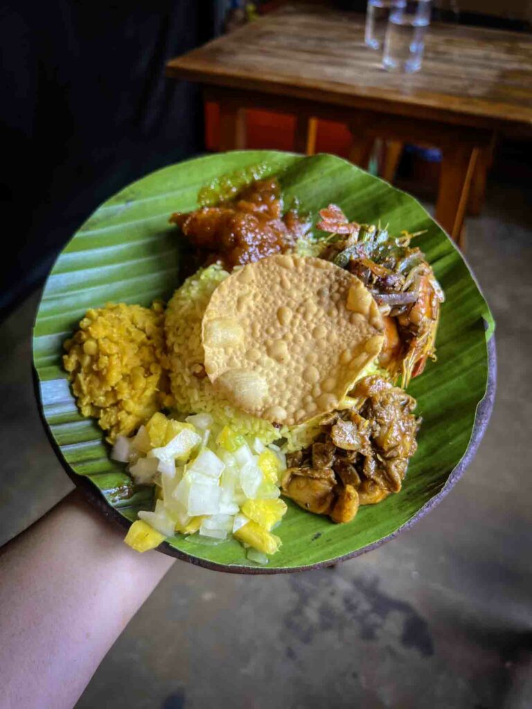 Plate of rice and curry in woman's hand at Mandiya restaurant in Kandy