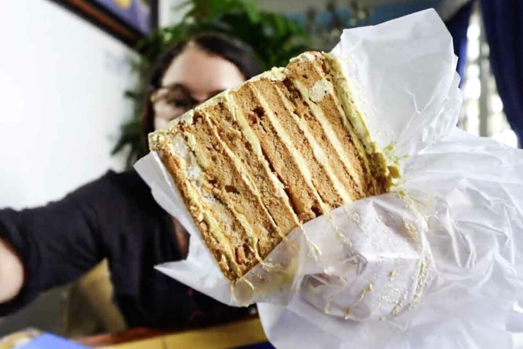 woman holds slice of sans rival cake dessert in Dumaguete