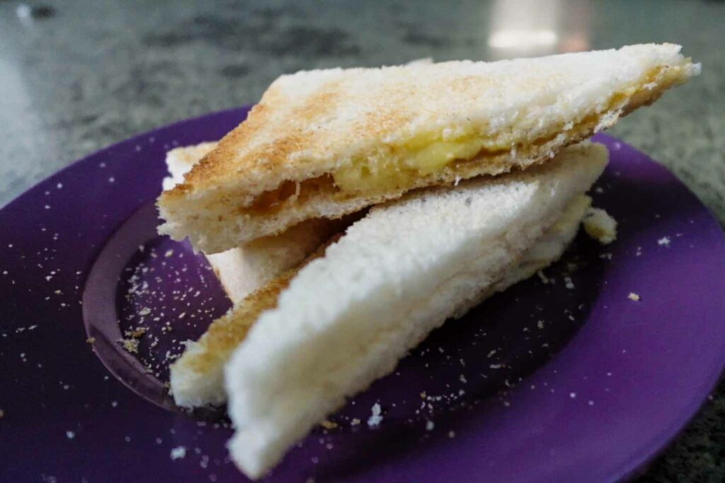 Most popular breakfast in Singapore, kaya toast on a purple plate, white toast with cold butter and pandan in centre