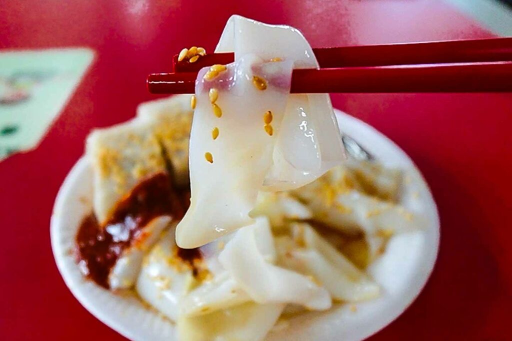 chee cheong fun, traditional breakfast in Singapore, focus on one of the noodles on a red table