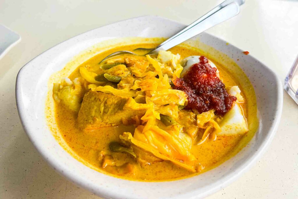 Singaporean breakfast known as lontong, compressed rice cakes in coconut curry with cabbage, tofu and sweet sambal