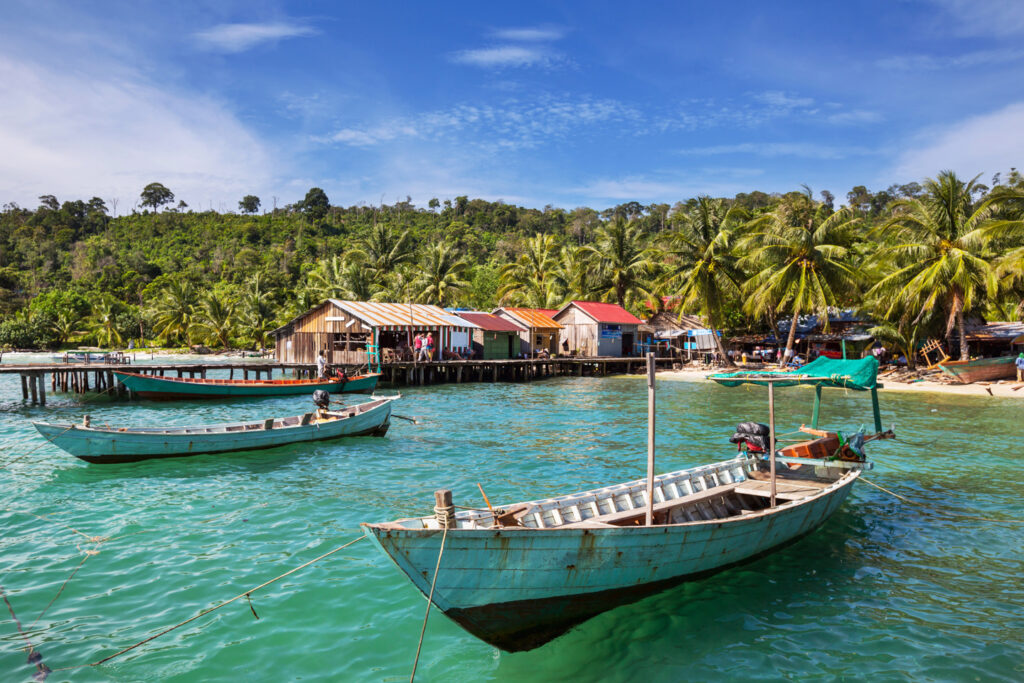 kep cambodia fishing boats on beautiful blue water with fishing village in background